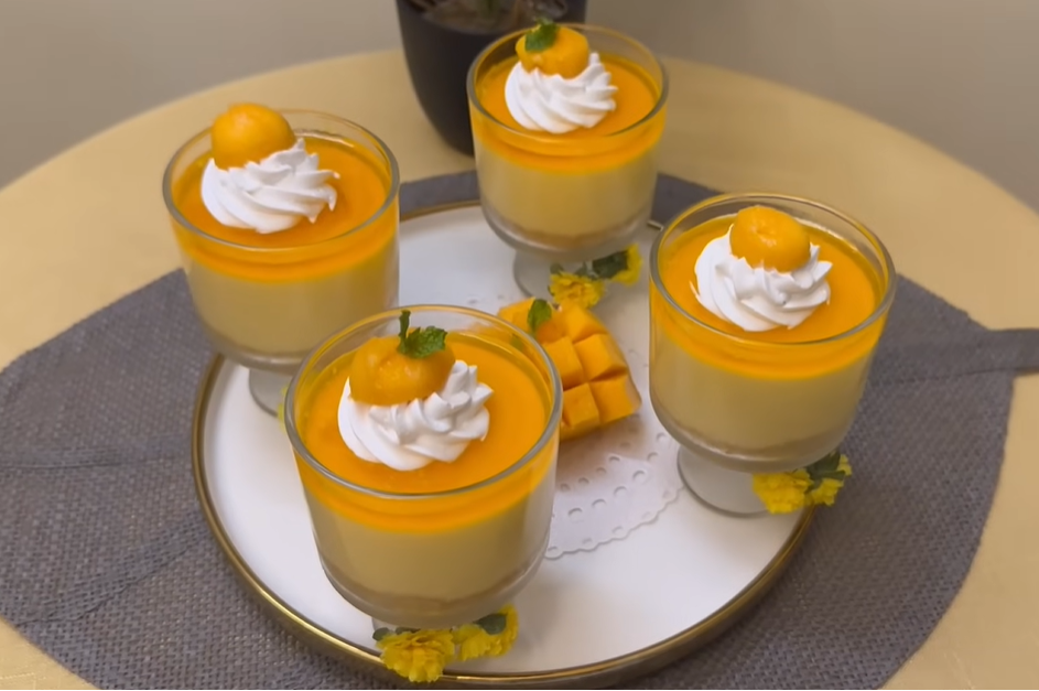 4 no bake mango cheesecake dessert cups seen from above, decorated with a swirl of whipped cream and chopped mangoes