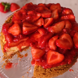 "Delicious strawberry cheesecake with a glossy strawberry compote and fresh strawberries on top, slice being served to showcase its creamy texture."