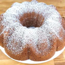 A timeless vanilla Bundt cake displayed on a stand, lightly dusted with powdered sugar.