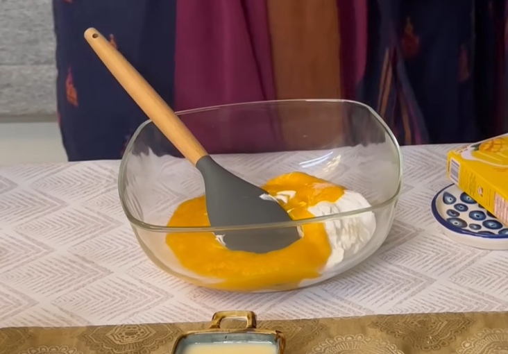 Add mango pulp on top of the whisked cream cheese in a glass bowl.