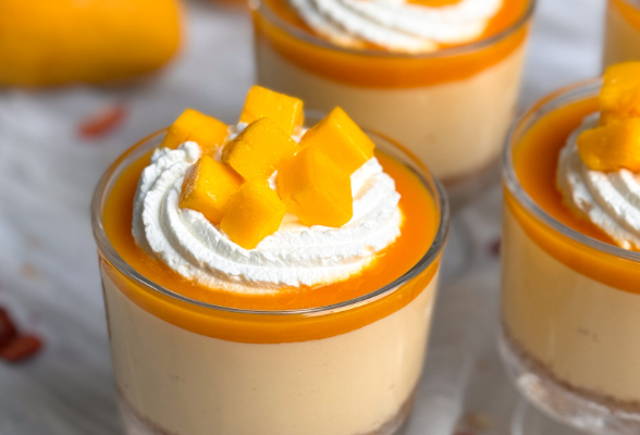 This description effectively portrays a visually enticing and delicious no-bake mango cheesecake cup, emphasizing its layers, textures, and vibrant decorations.