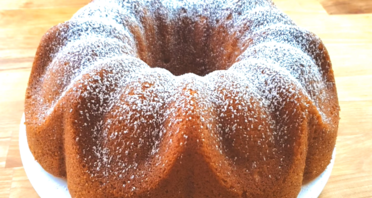 A timeless vanilla Bundt cake displayed on a stand, lightly dusted with powdered sugar.