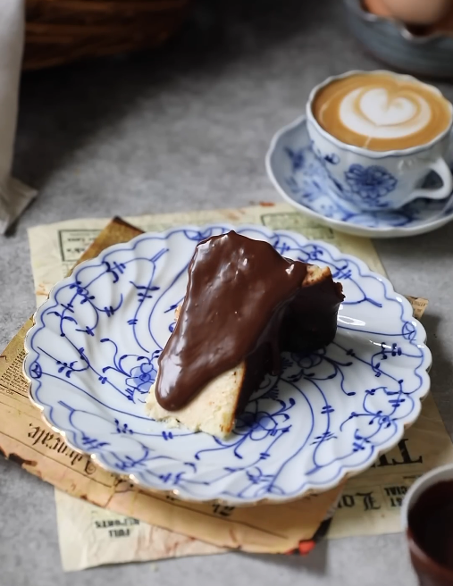 A slice of Basque cheesecake topped with rich chocolate ganache.






