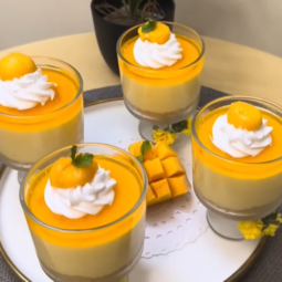 This description captures the essence of a visually appealing and delicious no-bake mango cheesecake cup, highlighting its layers, textures, and vibrant decorations.