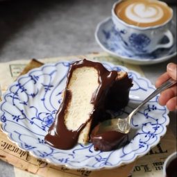 A golden brown Basque cheesecake on parchment paper, with a slice being removed to show its creamy interior.