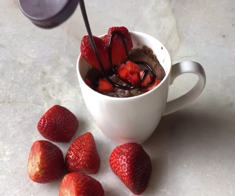 "A cozy cup filled with a rich, moist chocolate mug cake, perfectly paired with fresh strawberries and a drizzle of melted chocolate on top. This indulgent treat is an easy, single-serving dessert that satisfies your sweet tooth in minutes."