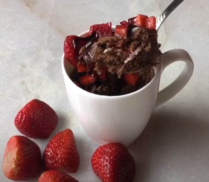 indulge in a decadent chocolate strawberry mug cake, with a spoon lifting a rich, moist bite from the center, showcasing its gooey, delicious texture.