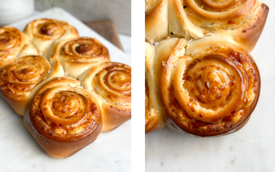 Side view of six golden cheesy bread rolls on a rustic serving board, topped with a glossy honey butter spread.