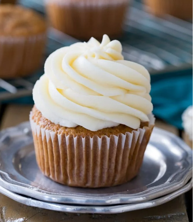 “Delicious cupcake topped with a smooth layer of cream cheese frosting, elegantly piped for a perfect finish.”