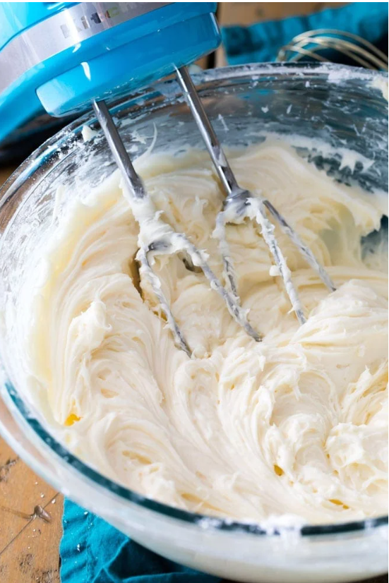 “A vibrant bowl of creamy cream cheese icing, perfect for spreading or decorating desserts.”