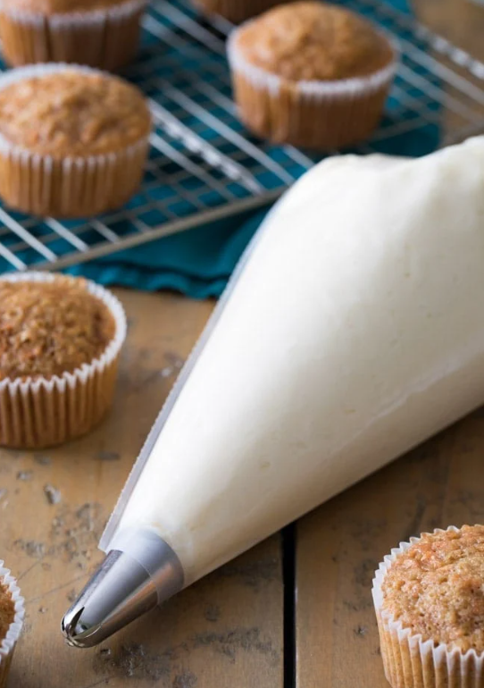 “Cream cheese frosting neatly packed in a pastry bag, ready for piping onto cupcakes and cakes.”



