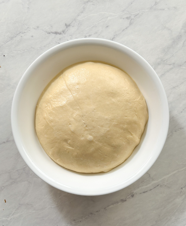 Perfectly risen dough in a white round bowl, ready for baking.