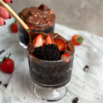 A spoon lifts a bite from a chocolate strawberry mug cake, revealing its rich, moist texture and decadent chocolatey goodness inside.