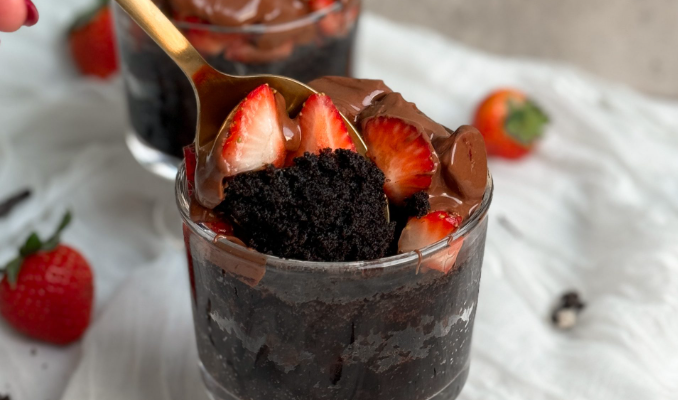 A spoon lifts a bite from a chocolate strawberry mug cake, revealing its rich, moist texture and decadent chocolatey goodness inside.